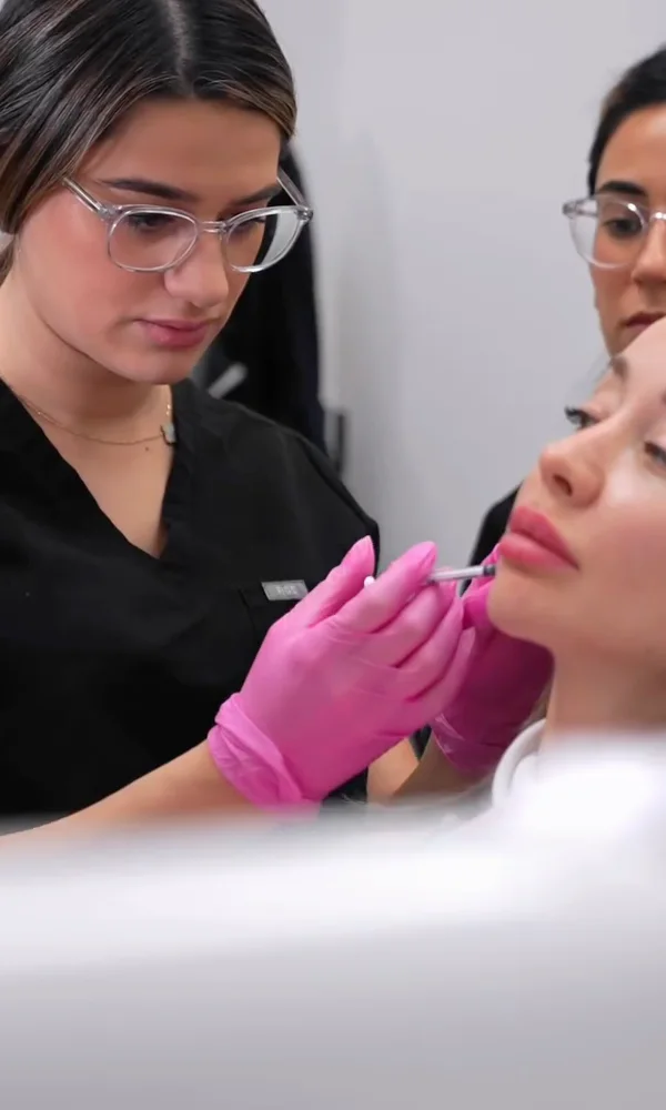 A trainee in safety glasses injecting a live patient under supervision at Contour Aesthetics, Greenpoint Brooklyn