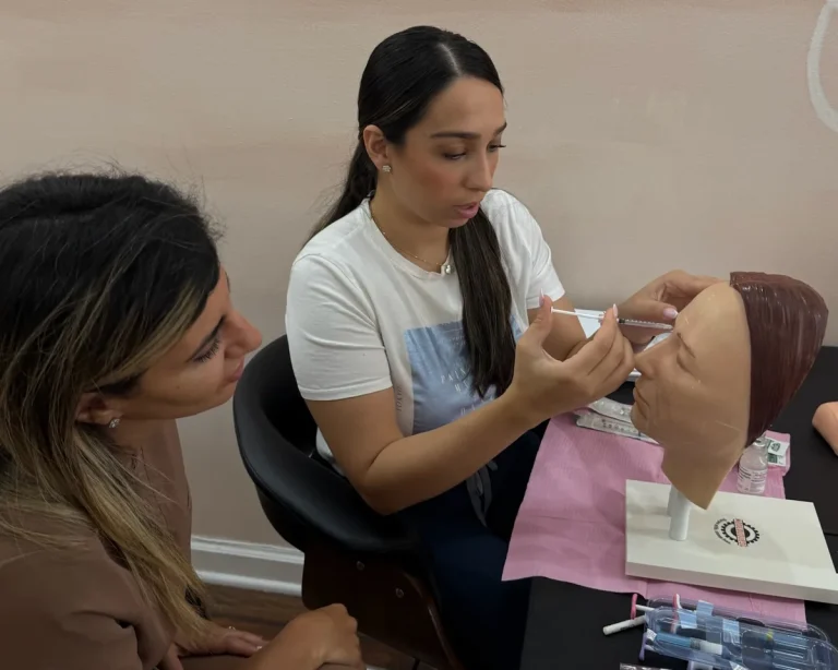 A trainee practises injection technique on a training head under an instructor's supervision at Contour Aesthetics